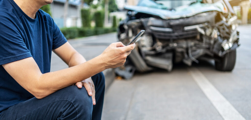 A man on his phone after a car accident. 