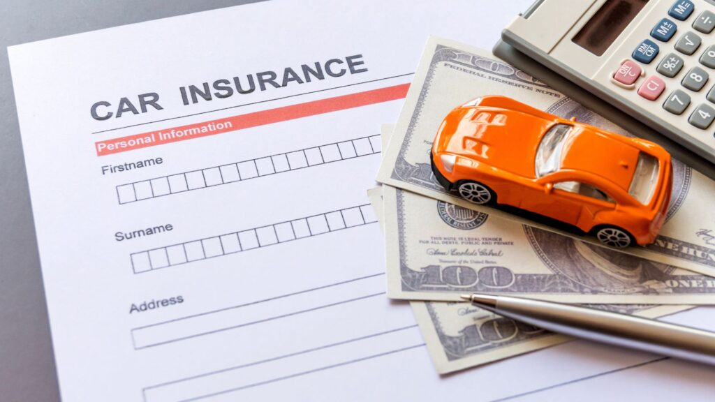A car insurance form with a calculator, toy car, and money right on top of it. 