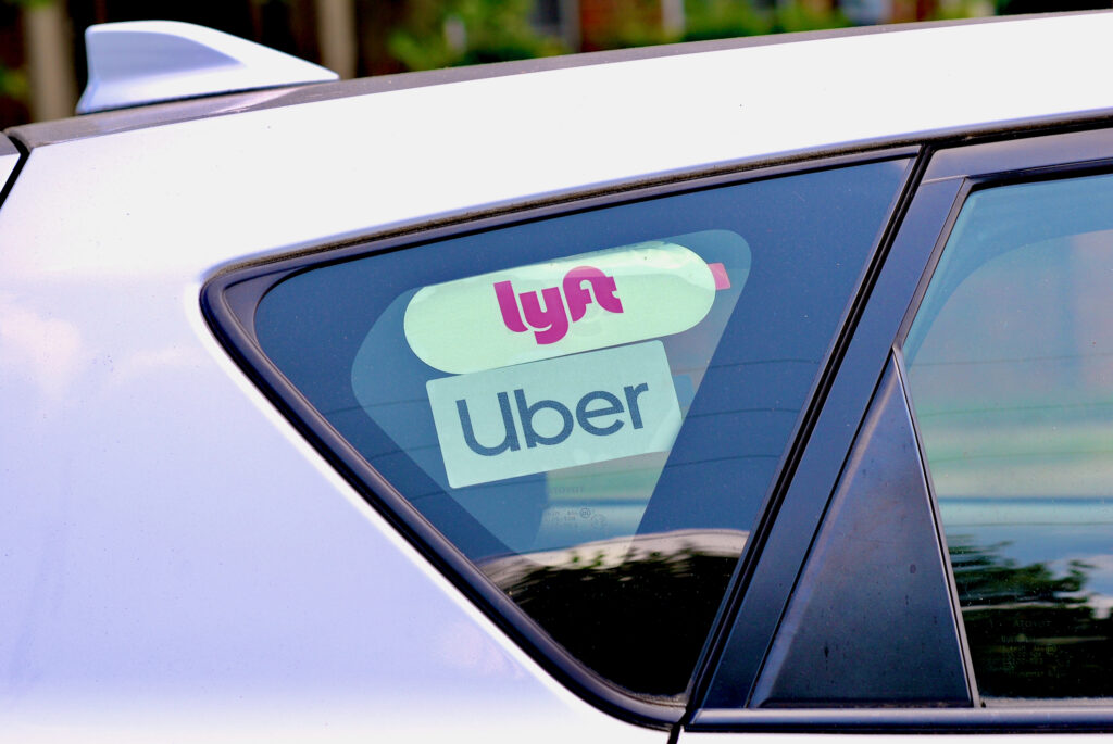 A car with an Uber and Lyft sticker on their back window.
