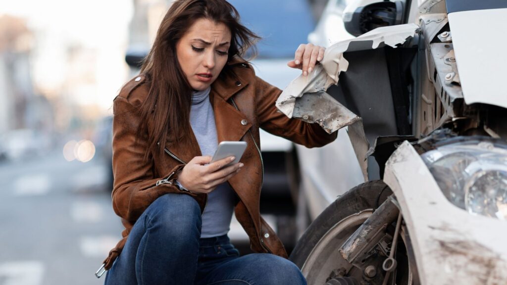 A woman on her phone, right after getting involved in a car accident.
