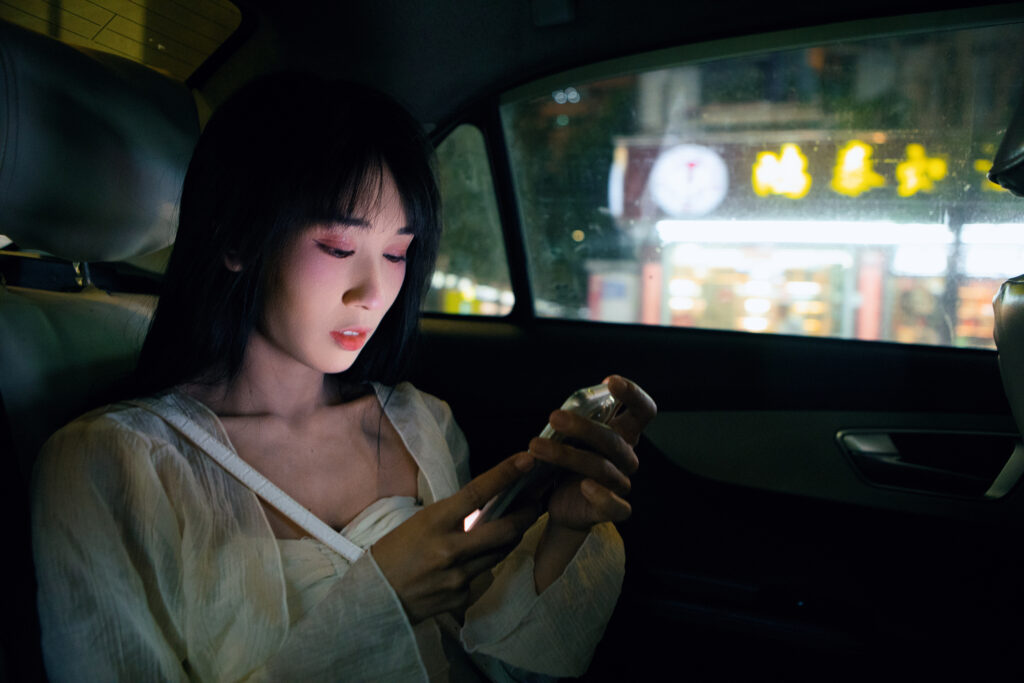 A woman looking at her phone during a trip in a rideshare service.