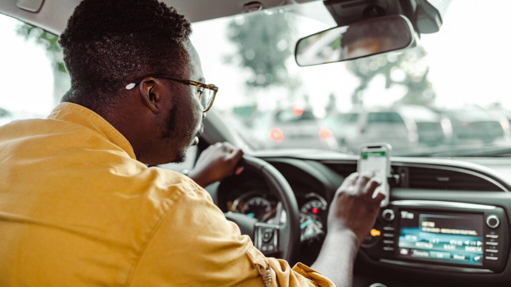 An Uber driver checking their phone while behind the wheel.
