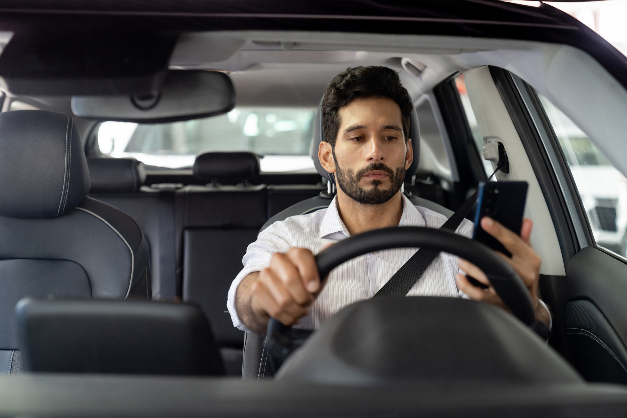 A man looking at his phone while driving.