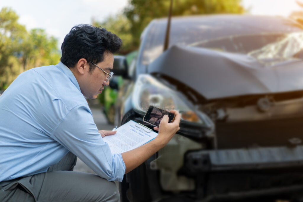 An insurance adjuster taking photos of a damaged car.
