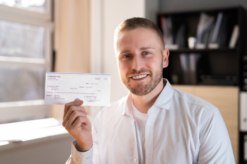 A man holding up a check while smiling.