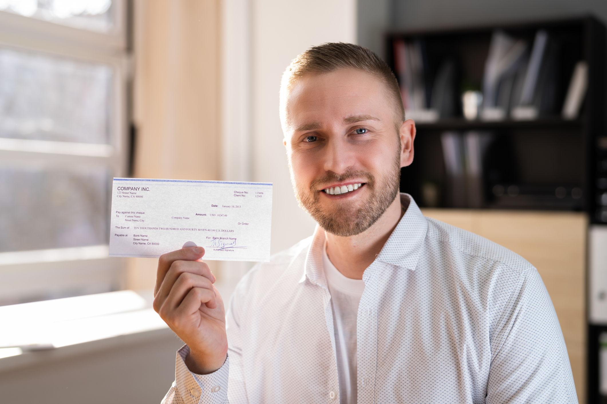 A man holding up a check while smiling.