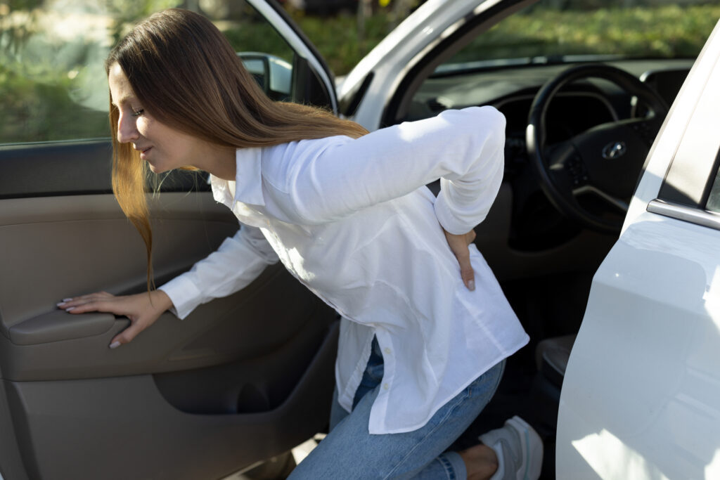 A woman with a back injury getting out of a car.