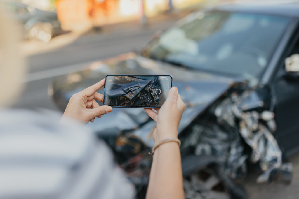 A person taking a photo of a car accident on their phone.