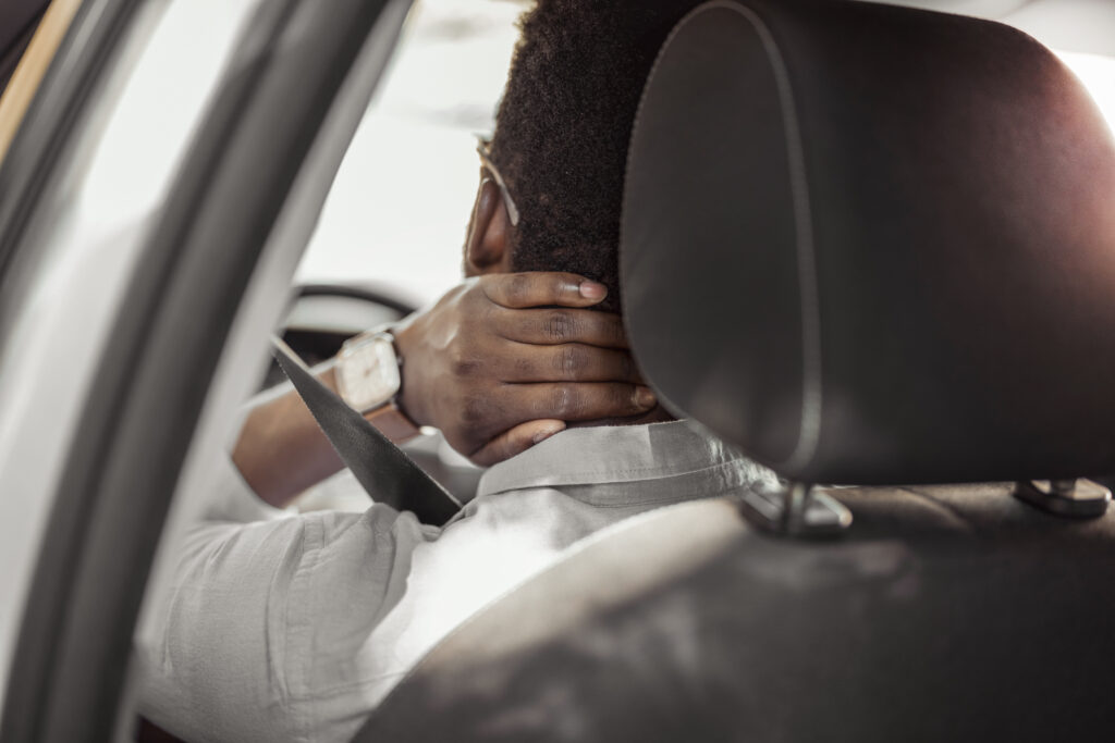 A man holding his neck in pain after an accident.