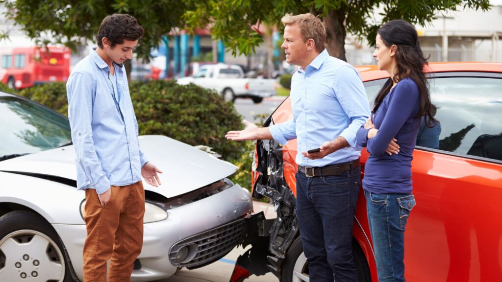 A young man getting yelled at by two people for a car accident. 