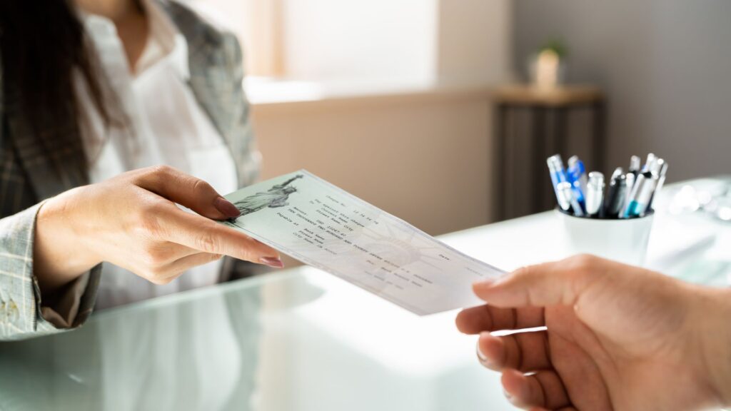 A woman handing off a check to another person. 