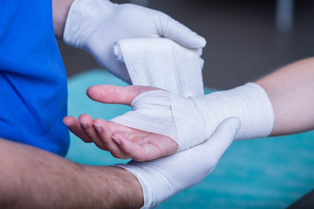 A doctor wrapping up a person's hand with gauze.