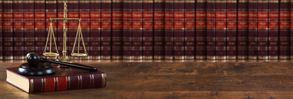 A row of legal books with a book and gavel on top of a table. 