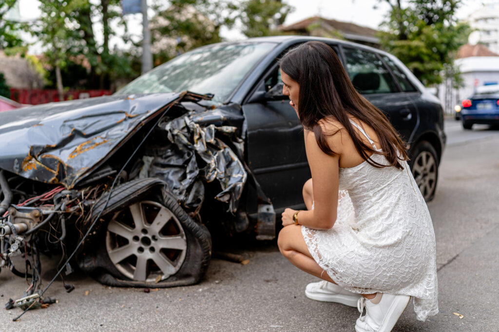 A woman looking at her car after an accident.