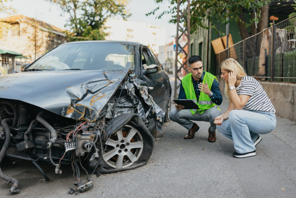 A woman and an insurance adjuster talking about the damage to a car. 
