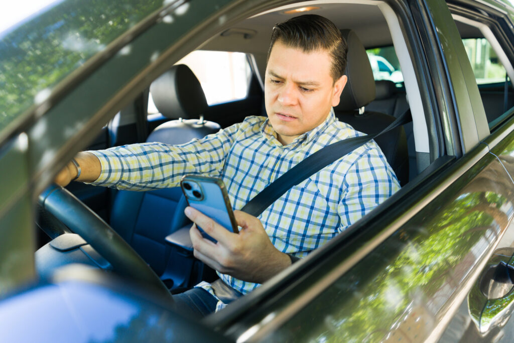 A rideshare driver looking at his phone confused,