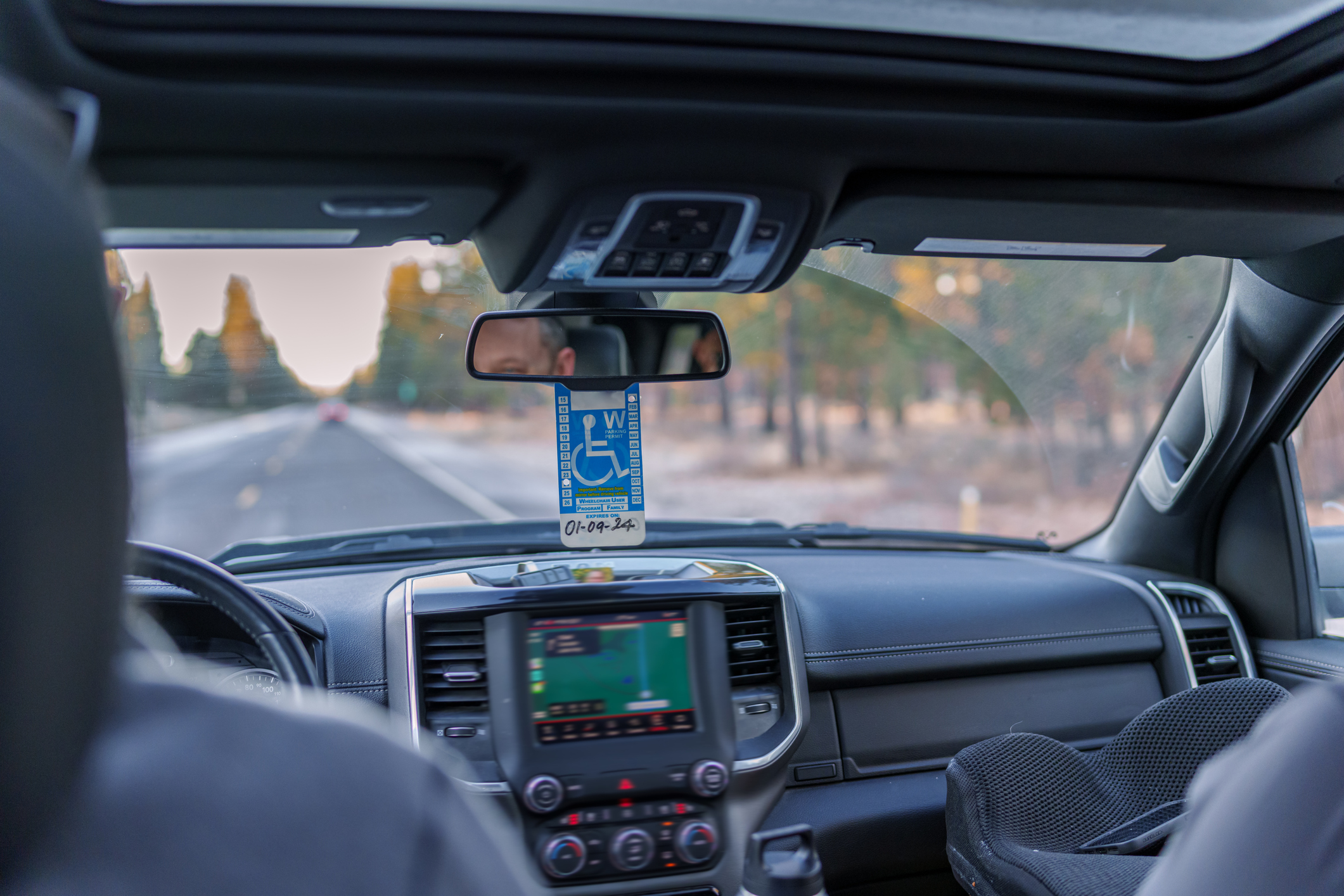 A car with a handicap sign hanging on the rearview mirror.