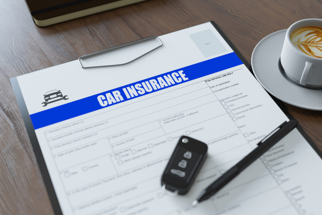 A car insurance policy with a key and pen on top of it.