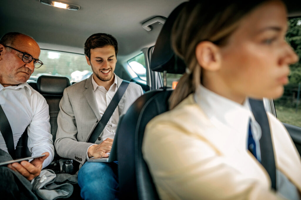 Two men sitting in the back of an Uber and talking. 