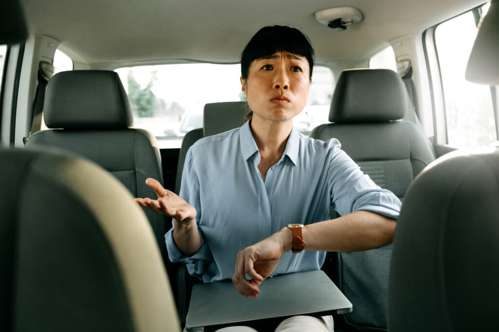 A angry woman in the backseat of a car. 