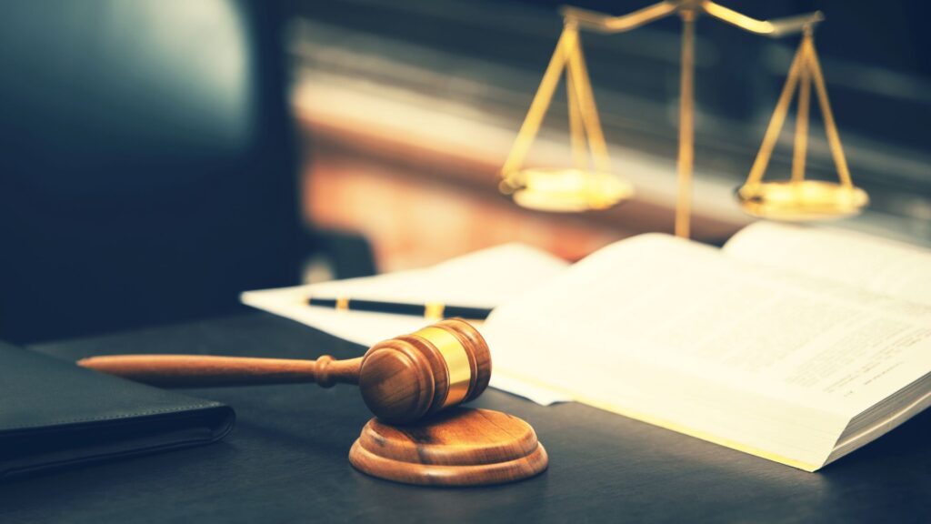 A gavel on a desk, right next to a book and a scale of justice.