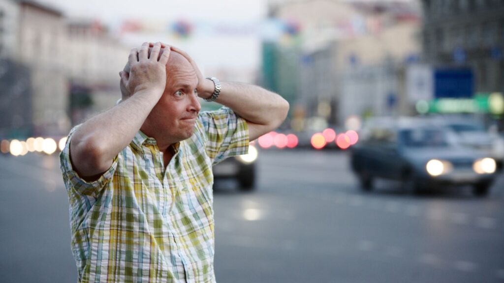A stressed out man with his hands on his head.
